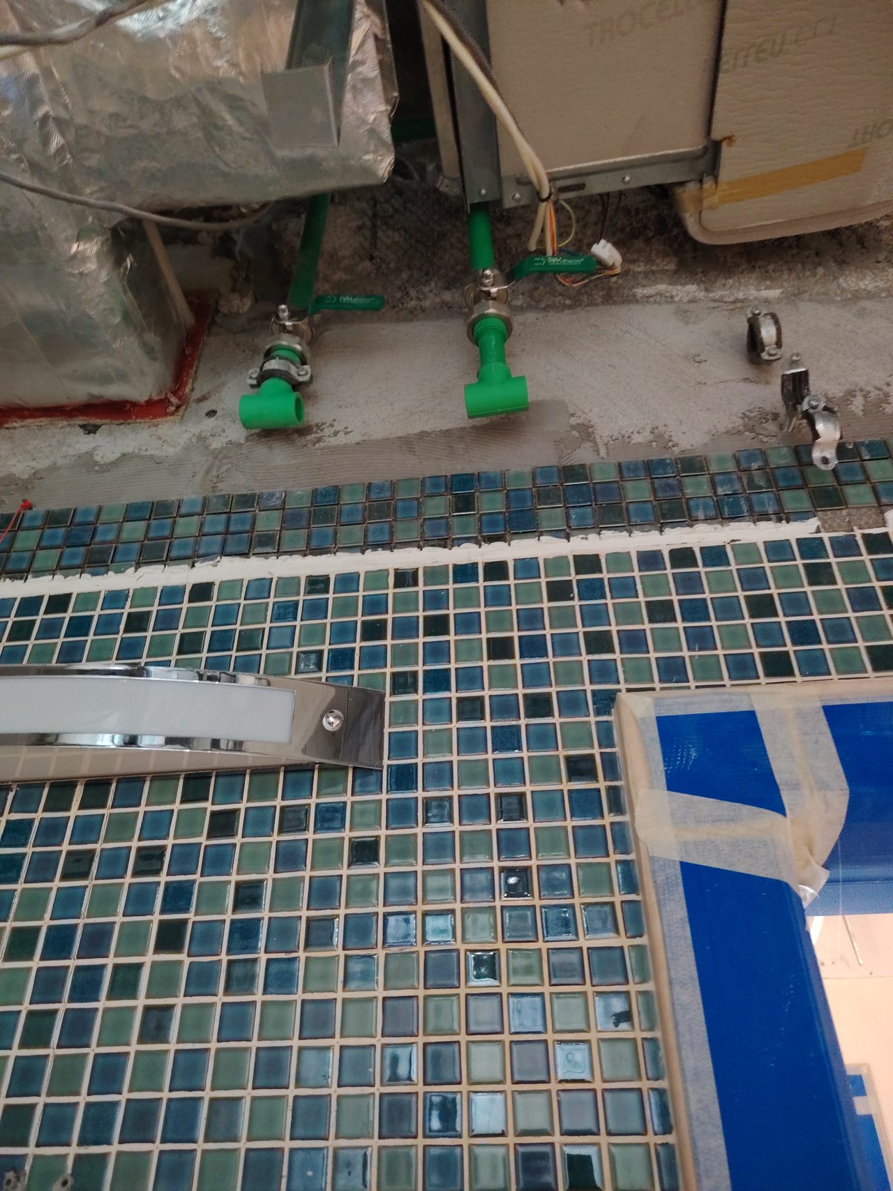 Connection of new green polypropylene pipes to the water supply system above the mosaic tiles