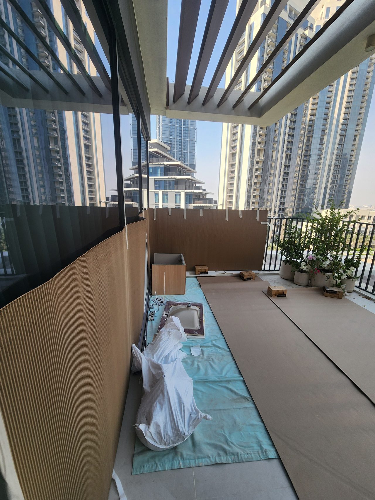 Surface protection on the balcony: the floor is covered with film and heavy cardboard, while railings and walls are protected with corrugated cardboard