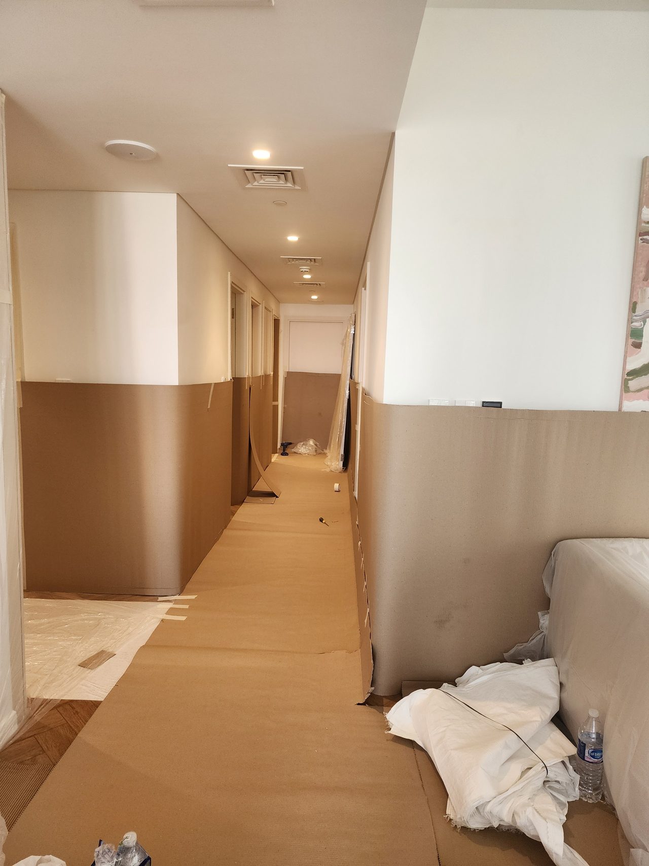 Corridor protection: walls are covered with corrugated cardboard up to head height, and the floor is fully lined with protective sheeting