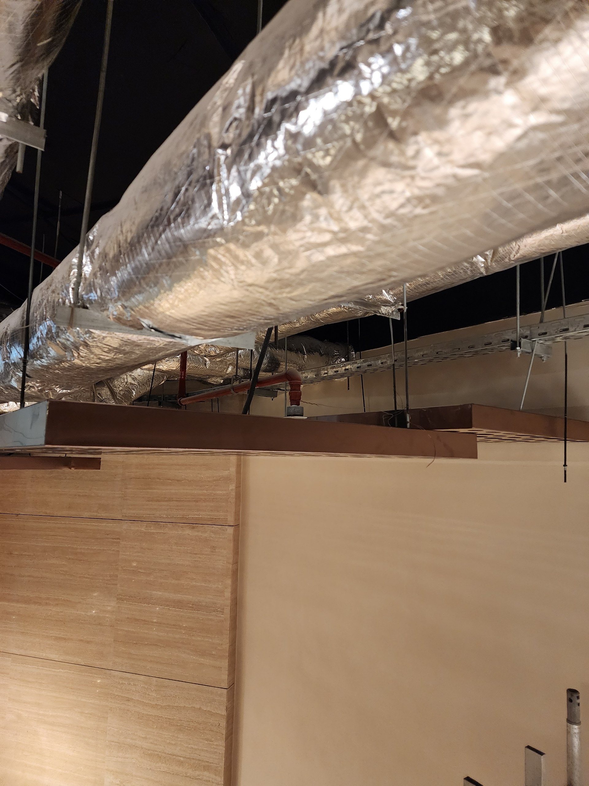 Side of a 50 mm metal ceiling panel under an insulated ventilation duct.