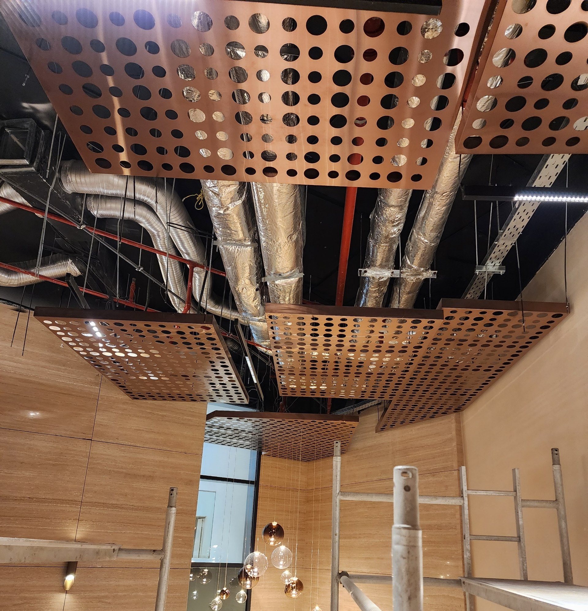 Stepped metal ceiling over a double-height hall with glass pendants in the void.