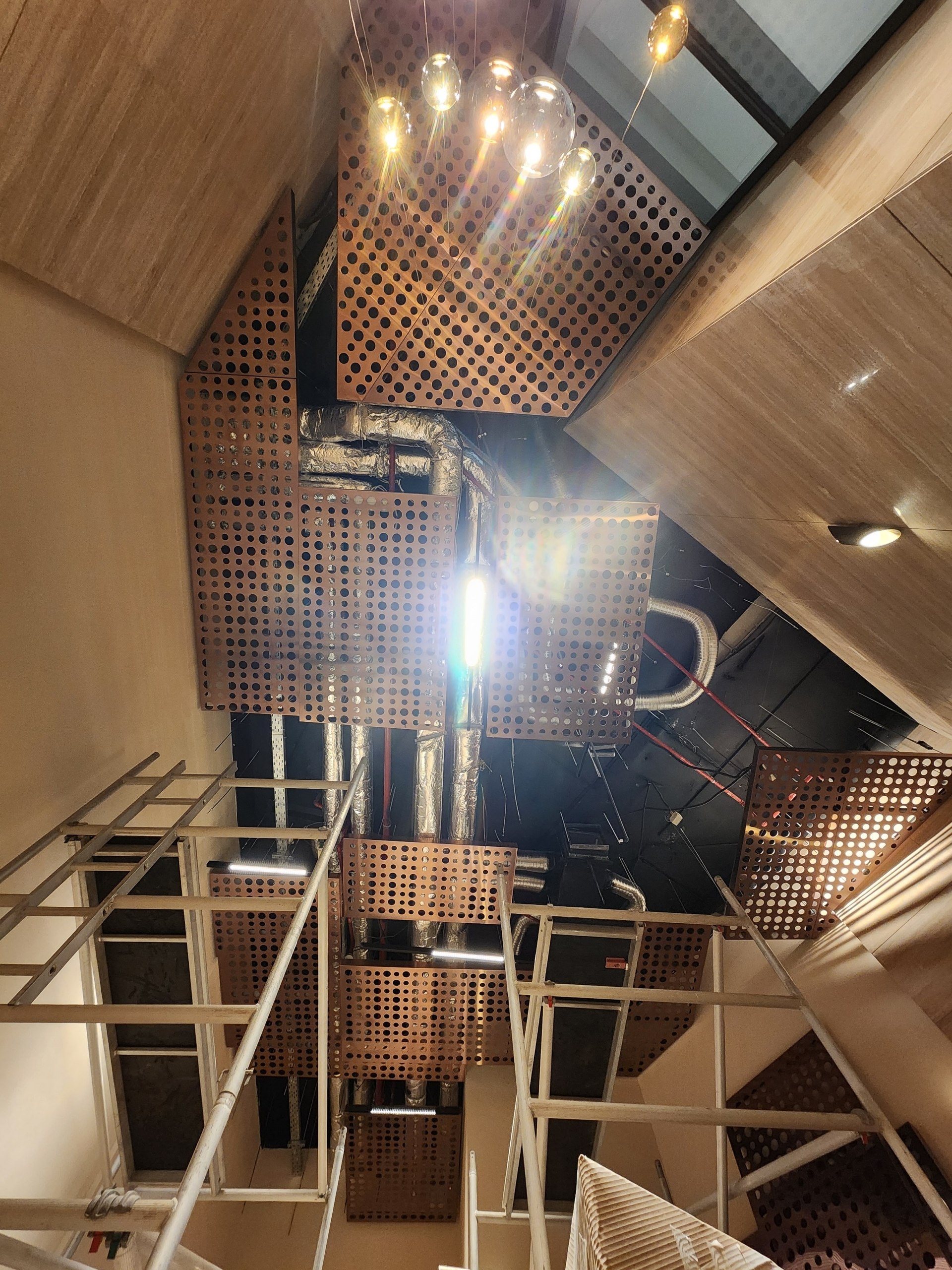 Full height of the hall: stepped perforated metal panels, ducts and scaffolding.